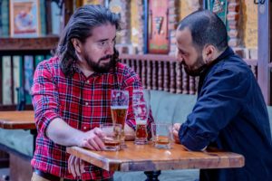 Two men drinking at a Norwich brewery.