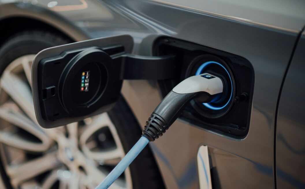 A close-up of an electric car being charged, showing the charging cable plugged into the vehicles port.